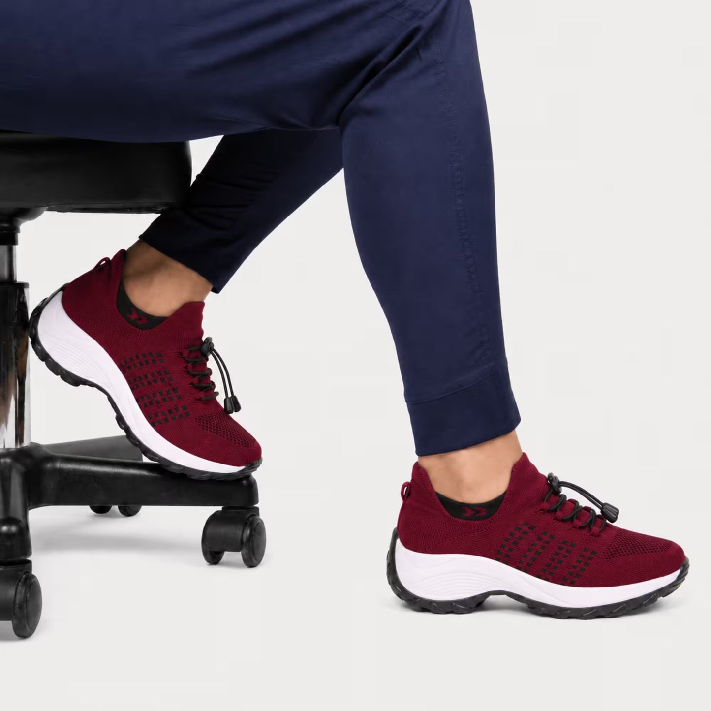 Burgundy/red knit lace-up sneakers on a person, white sole and black outsole